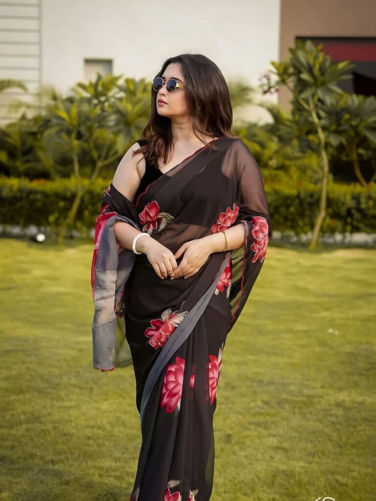 A lady in black saree with digital pink flower