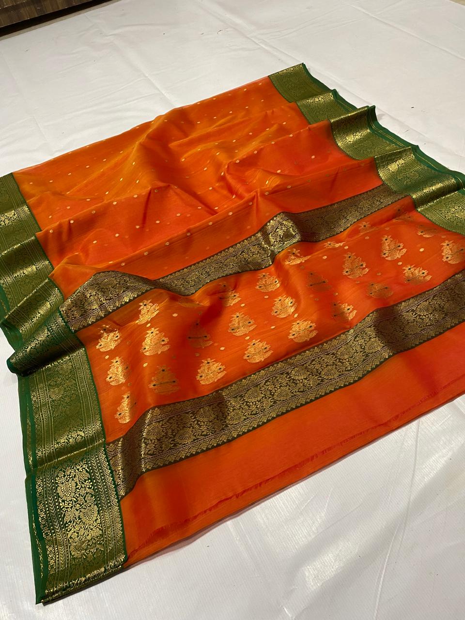 Open view of a Vibrant Mango Orange Chanderi Katan Silk Saree featuring traditional gold zari floral motifs on the lower half and a deep forest green border. Perfect for wedding receptions and festive luxury